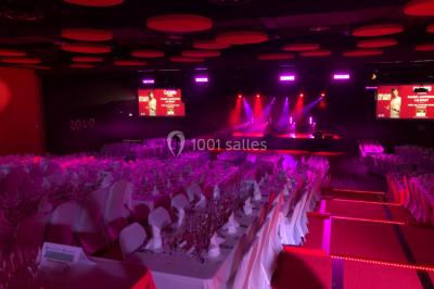 Bâtiment moderne en bord de rivière, entouré de verdure, avec un pont piétonnier au premier plan.