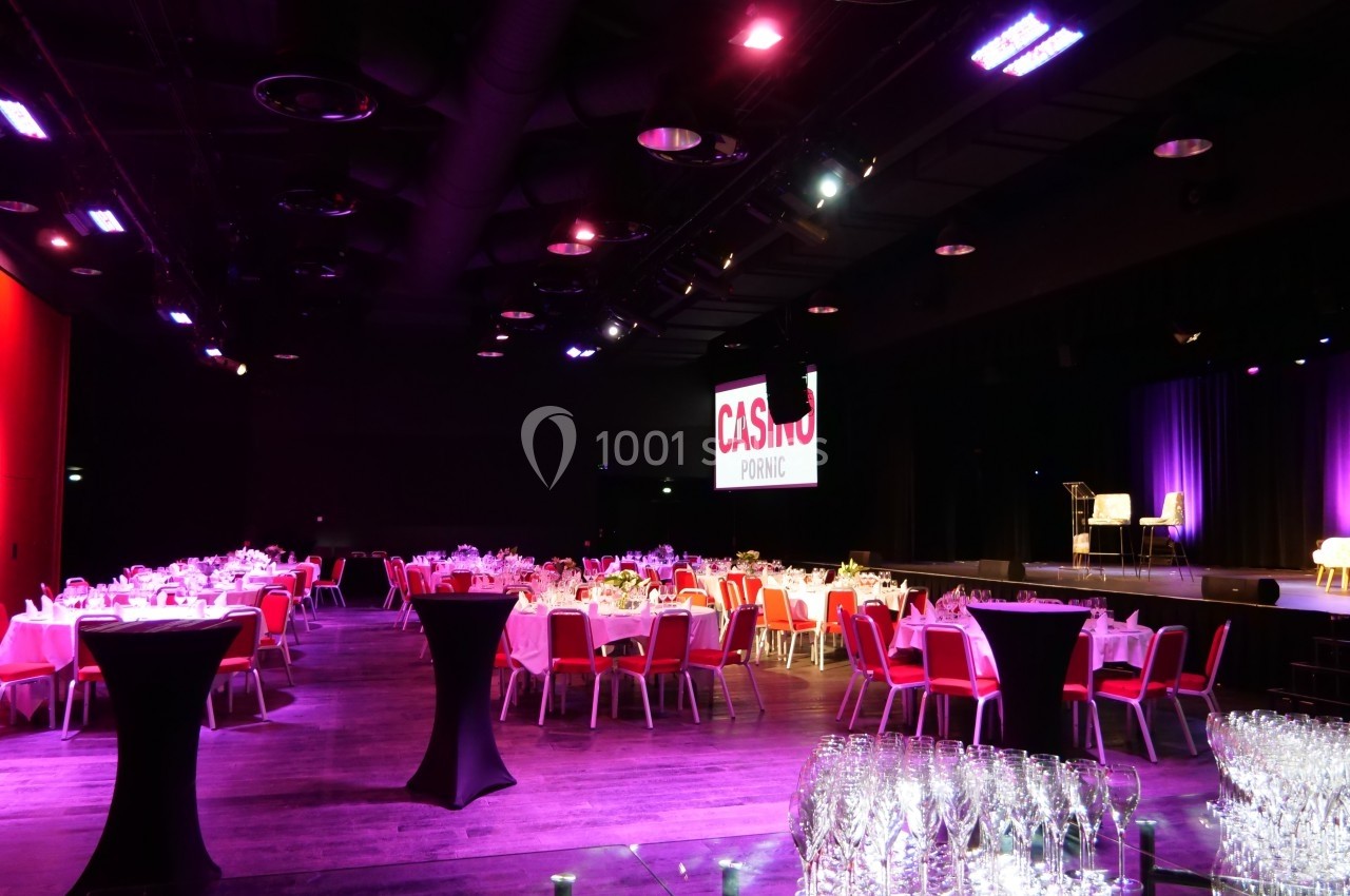 Salle de réception avec tables dressées, éclairage tamisé et écran affichant ’Casino Pornic’ en arrière-plan.