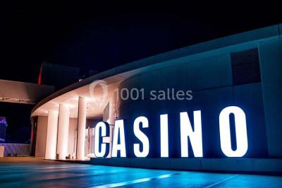 Bâtiment circulaire moderne illuminé la nuit, avec un chemin éclairé et des rampes décorées de lumières.