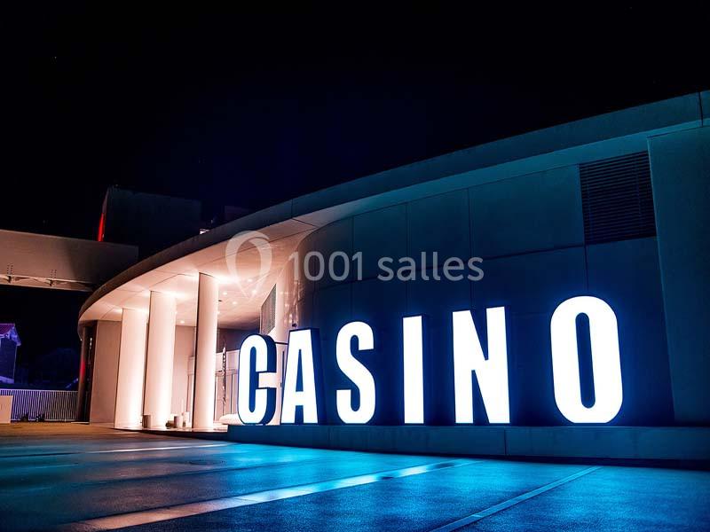 Façade d'un bâtiment moderne avec le mot ’CASINO’ illuminé en grandes lettres blanches la nuit.