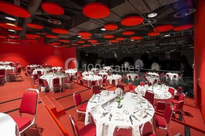 Bâtiment circulaire moderne illuminé la nuit, avec un chemin éclairé et des rampes décorées de lumières.