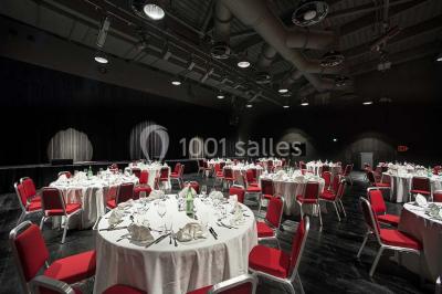 Bâtiment circulaire moderne illuminé la nuit, avec un chemin éclairé et des rampes décorées de lumières.