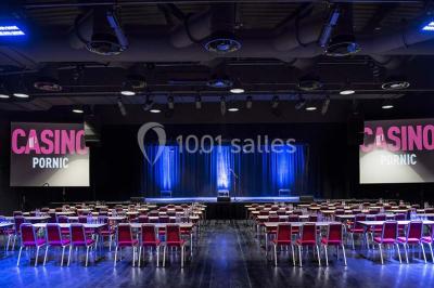 Bâtiment circulaire moderne illuminé la nuit, avec un chemin éclairé et des rampes décorées de lumières.