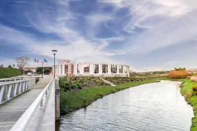 Bâtiment circulaire moderne illuminé la nuit, avec un chemin éclairé et des rampes décorées de lumières.