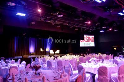 Bâtiment circulaire moderne illuminé la nuit, avec un chemin éclairé et des rampes décorées de lumières.