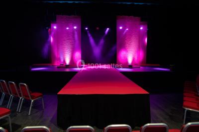 Bâtiment circulaire moderne illuminé la nuit, avec un chemin éclairé et des rampes décorées de lumières.