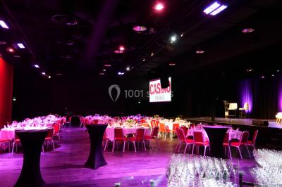 Bâtiment circulaire moderne illuminé la nuit, avec un chemin éclairé et des rampes décorées de lumières.