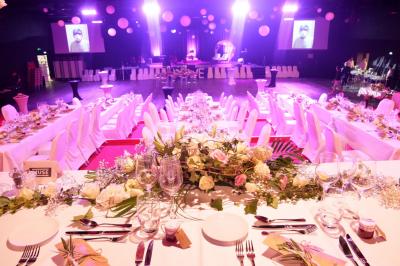 Bâtiment circulaire moderne illuminé la nuit, avec un chemin éclairé et des rampes décorées de lumières.