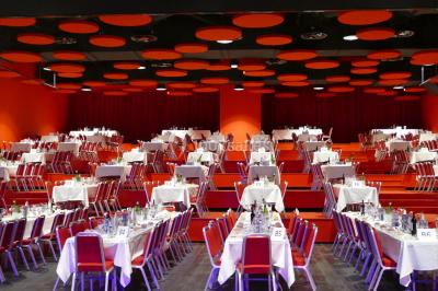 Bâtiment circulaire moderne illuminé la nuit, avec un chemin éclairé et des rampes décorées de lumières.