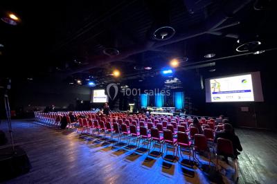 Bâtiment circulaire moderne illuminé la nuit, avec un chemin éclairé et des rampes décorées de lumières.