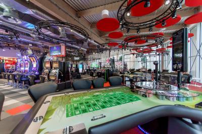 Bâtiment circulaire moderne illuminé la nuit, avec un chemin éclairé et des rampes décorées de lumières.