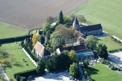 Un couple en tenue de mariage marche dans une allée extérieure décorée, entourée de chaises et de pétales de fleurs.