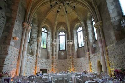 Un couple en tenue de mariage marche dans une allée extérieure décorée, entourée de chaises et de pétales de fleurs.