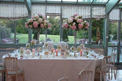 Un couple en tenue de mariage marche dans une allée extérieure décorée, entourée de chaises et de pétales de fleurs.