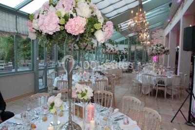 Un couple en tenue de mariage marche dans une allée extérieure décorée, entourée de chaises et de pétales de fleurs.