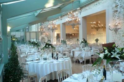 Un couple en tenue de mariage marche dans une allée extérieure décorée, entourée de chaises et de pétales de fleurs.
