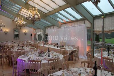 Un couple en tenue de mariage marche dans une allée extérieure décorée, entourée de chaises et de pétales de fleurs.