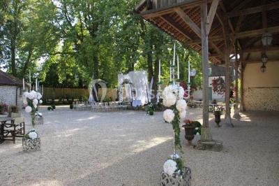 Un couple en tenue de mariage marche dans une allée extérieure décorée, entourée de chaises et de pétales de fleurs.