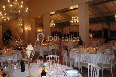 Un couple en tenue de mariage marche dans une allée extérieure décorée, entourée de chaises et de pétales de fleurs.