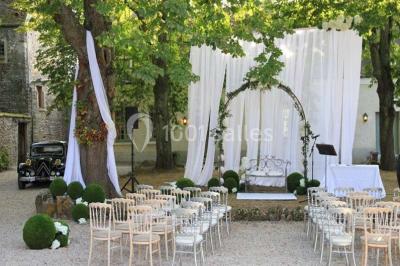 Un couple en tenue de mariage marche dans une allée extérieure décorée, entourée de chaises et de pétales de fleurs.