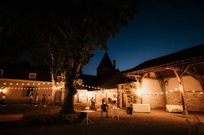 Un couple en tenue de mariage marche dans une allée extérieure décorée, entourée de chaises et de pétales de fleurs.