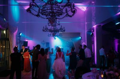 Un couple en tenue de mariage marche dans une allée extérieure décorée, entourée de chaises et de pétales de fleurs.