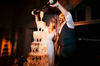 Un couple en tenue de mariage marche dans une allée extérieure décorée, entourée de chaises et de pétales de fleurs.