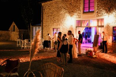 Un couple en tenue de mariage marche dans une allée extérieure décorée, entourée de chaises et de pétales de fleurs.