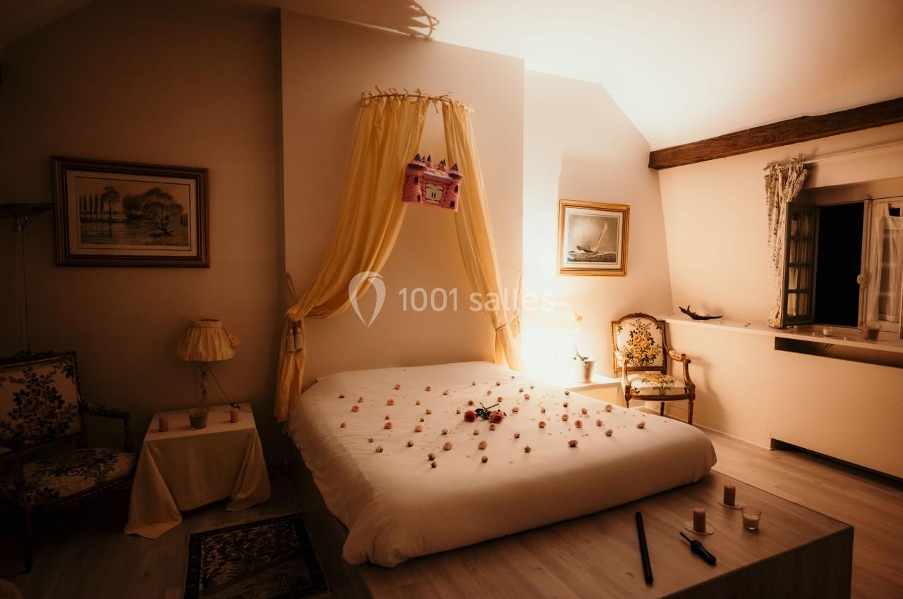 Lit double décoré de pétales de fleurs dans une chambre chaleureuse avec lumière tamisée et mobilier classique.