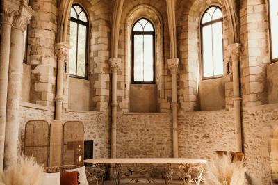 Un couple en tenue de mariage marche dans une allée extérieure décorée, entourée de chaises et de pétales de fleurs.