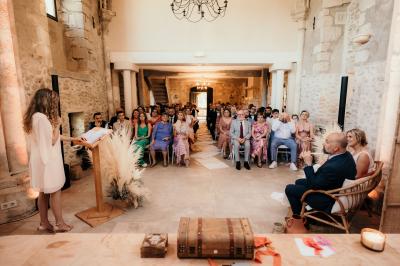 Un couple en tenue de mariage marche dans une allée extérieure décorée, entourée de chaises et de pétales de fleurs.