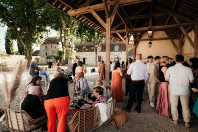 Un couple en tenue de mariage marche dans une allée extérieure décorée, entourée de chaises et de pétales de fleurs.