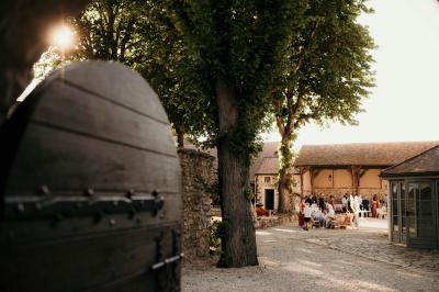 Un couple en tenue de mariage marche dans une allée extérieure décorée, entourée de chaises et de pétales de fleurs.