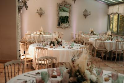 Un couple en tenue de mariage marche dans une allée extérieure décorée, entourée de chaises et de pétales de fleurs.