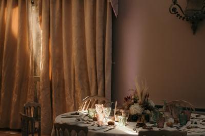 Un couple en tenue de mariage marche dans une allée extérieure décorée, entourée de chaises et de pétales de fleurs.
