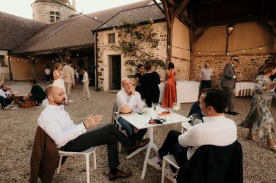 Un couple en tenue de mariage marche dans une allée extérieure décorée, entourée de chaises et de pétales de fleurs.