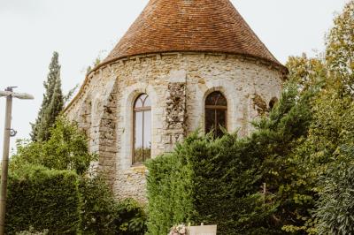 Un couple en tenue de mariage marche dans une allée extérieure décorée, entourée de chaises et de pétales de fleurs.