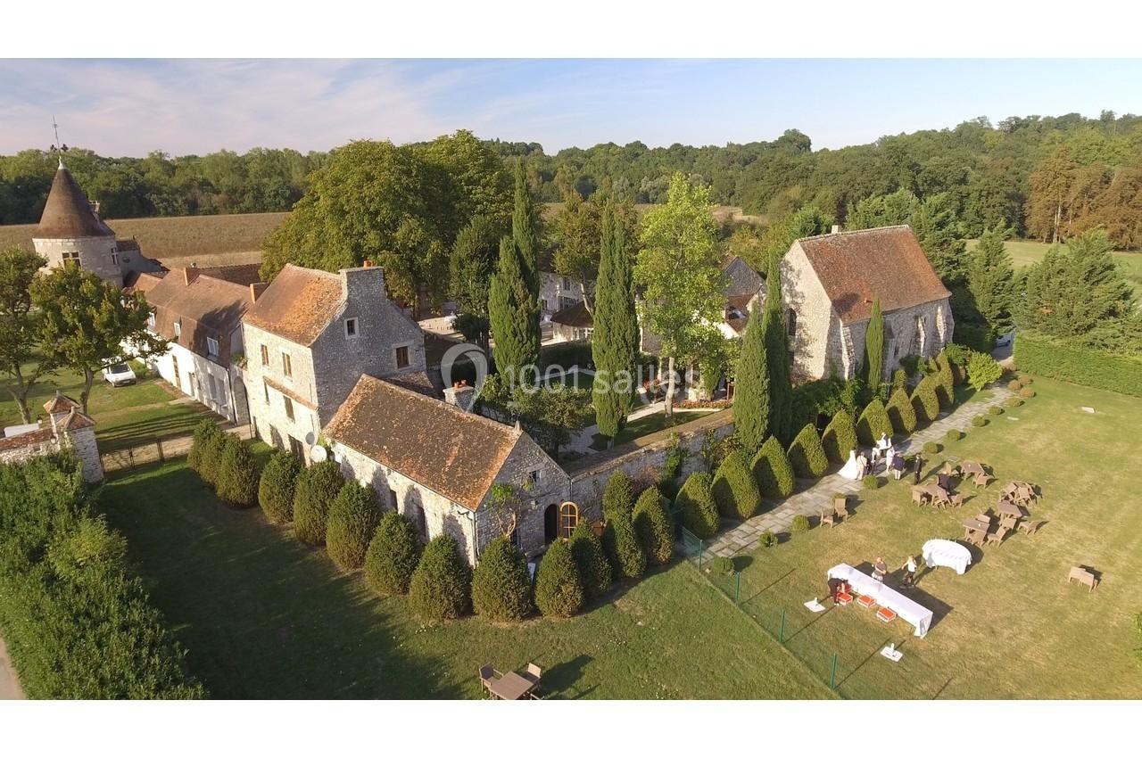 Vue aérienne d'un domaine avec bâtiments en pierre, toits en tuiles, jardins arborés et espaces aménagés en plein air.