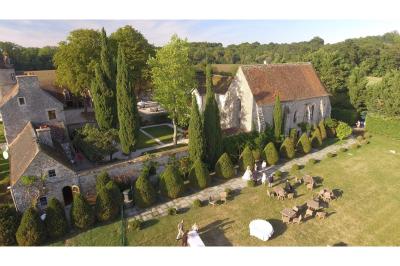 Un couple en tenue de mariage marche dans une allée extérieure décorée, entourée de chaises et de pétales de fleurs.