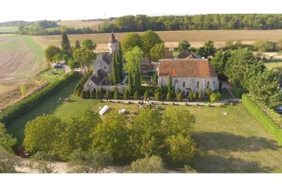 Un couple en tenue de mariage marche dans une allée extérieure décorée, entourée de chaises et de pétales de fleurs.