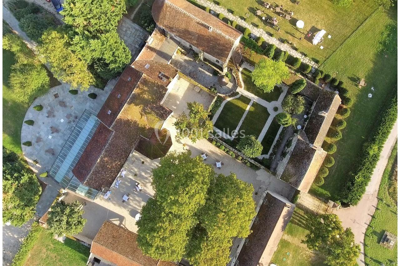Vue aérienne d'un domaine avec bâtiments en pierre, jardin à la française et espaces verts environnants.