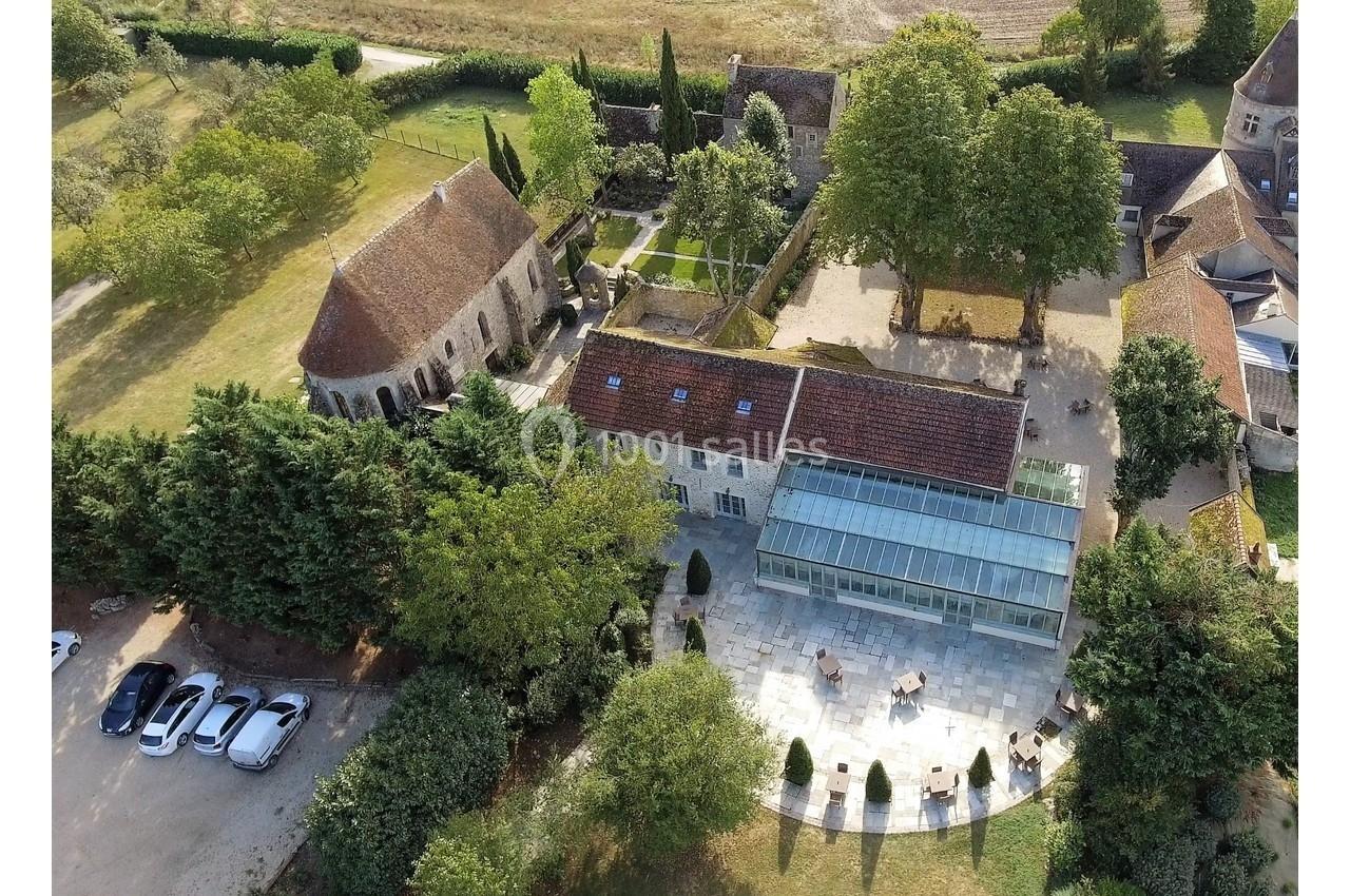 Vue aérienne d'un domaine avec bâtiments anciens, jardin aménagé, terrasse et voitures stationnées.