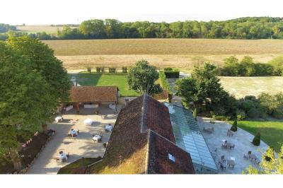Un couple en tenue de mariage marche dans une allée extérieure décorée, entourée de chaises et de pétales de fleurs.