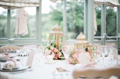Un couple en tenue de mariage marche dans une allée extérieure décorée, entourée de chaises et de pétales de fleurs.