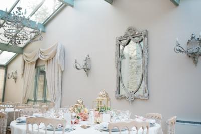 Un couple en tenue de mariage marche dans une allée extérieure décorée, entourée de chaises et de pétales de fleurs.