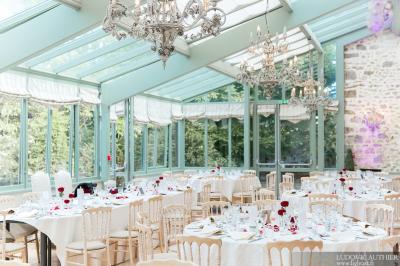 Un couple en tenue de mariage marche dans une allée extérieure décorée, entourée de chaises et de pétales de fleurs.