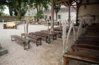 Un couple en tenue de mariage marche dans une allée extérieure décorée, entourée de chaises et de pétales de fleurs.