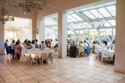 Un couple en tenue de mariage marche dans une allée extérieure décorée, entourée de chaises et de pétales de fleurs.