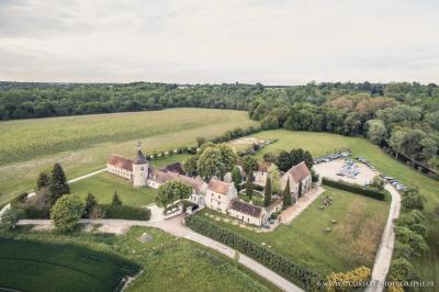 Un couple en tenue de mariage marche dans une allée extérieure décorée, entourée de chaises et de pétales de fleurs.