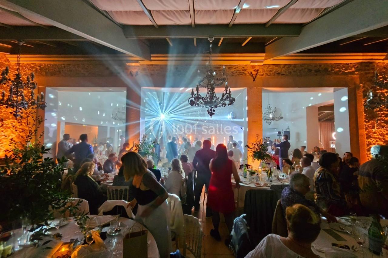 Salle de réception animée avec des invités dansant sous des jeux de lumière colorés et une ambiance festive.